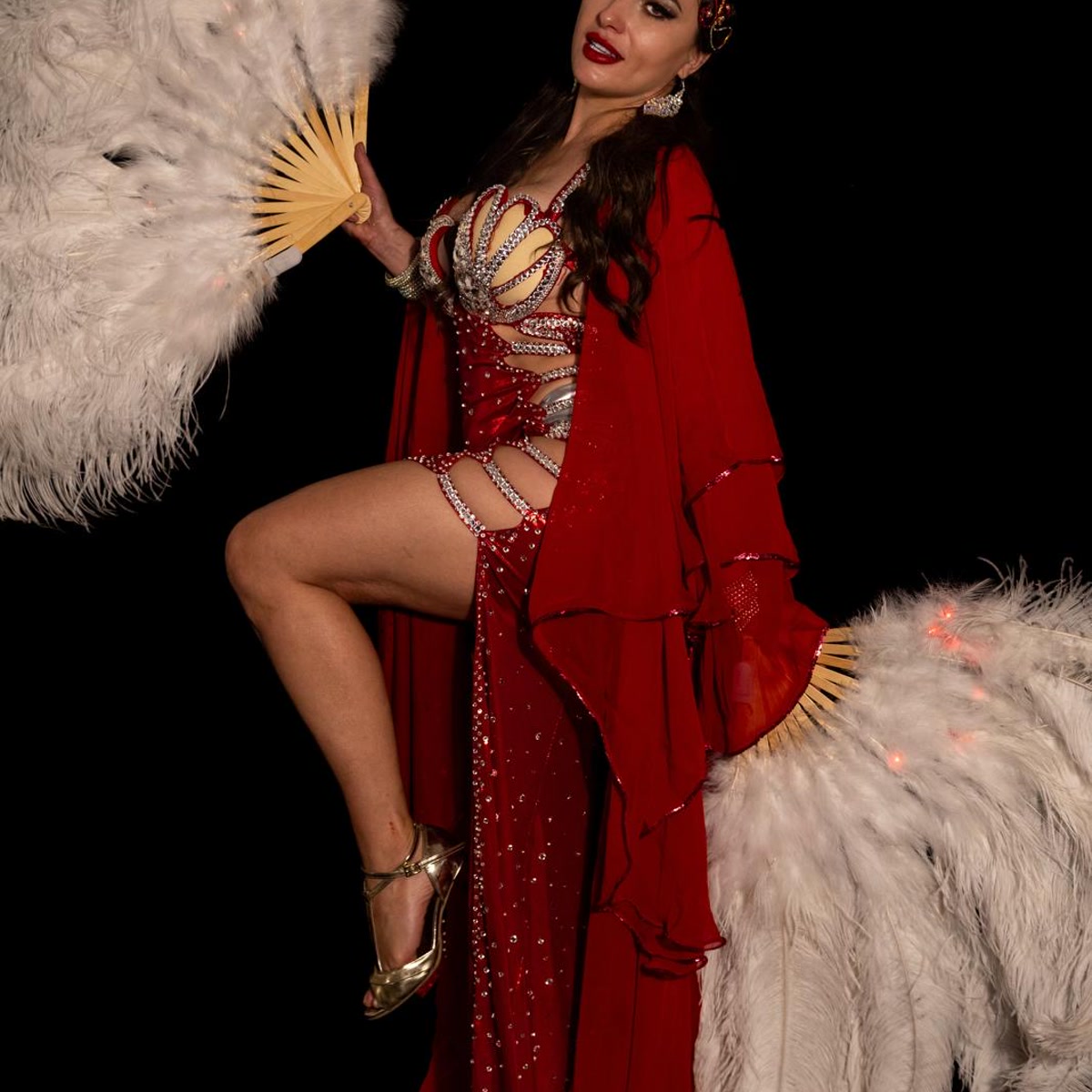 Ivanna posing with ostrich fans in a red cabaret costume