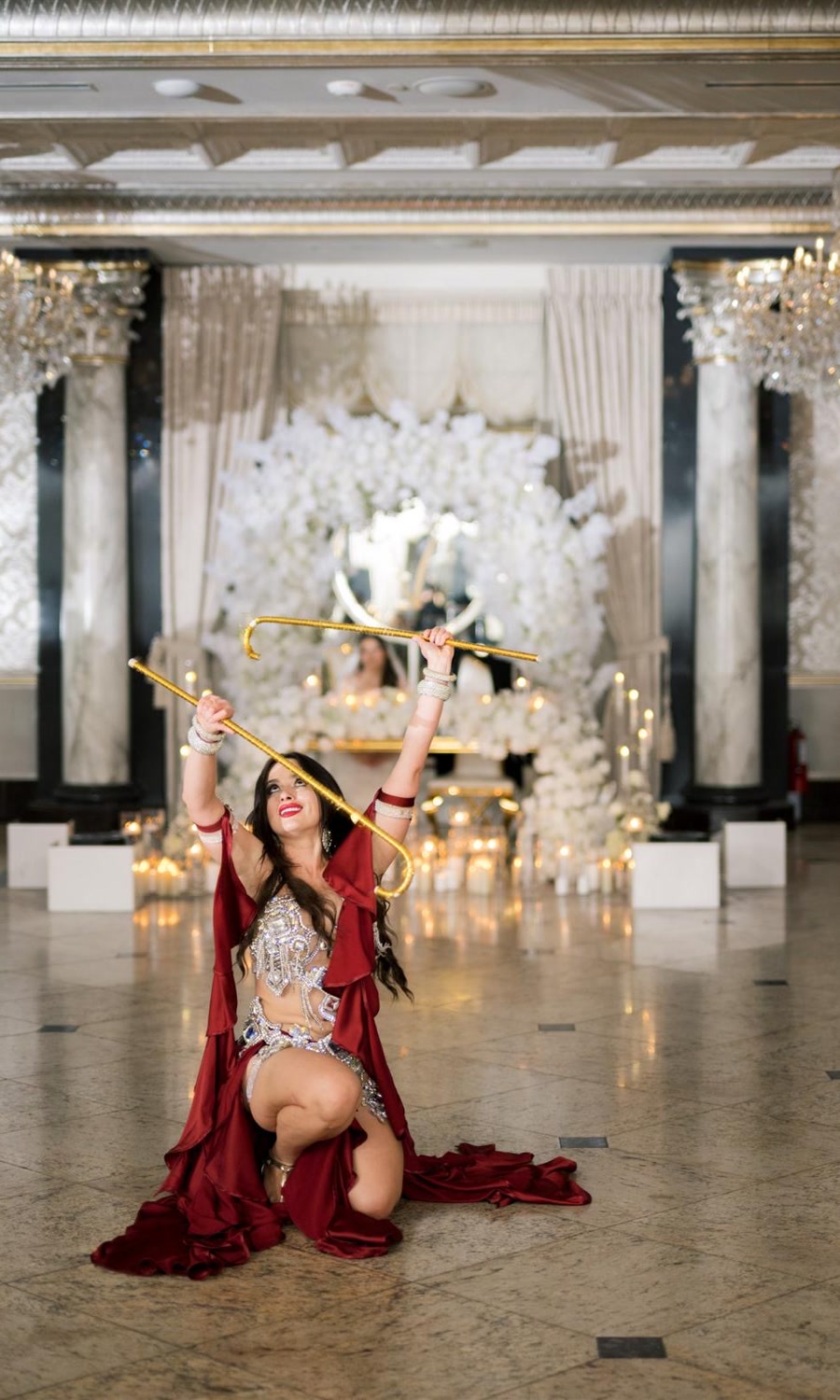 Ivanna kneeling with golden canes in a candlelit ballroom